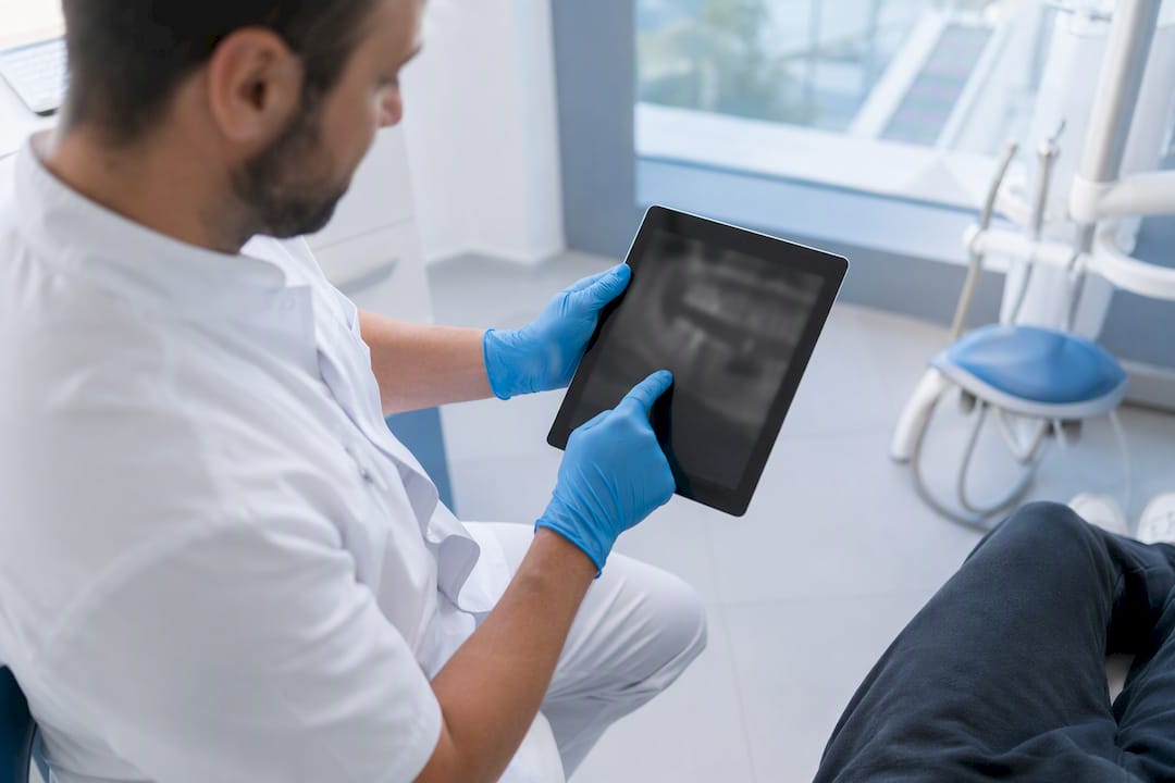 Zobozdravnik na tablici pacientu razlaga CBCT posnetek.